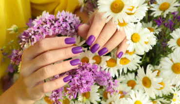 Manicure design with a matte lilac coating over a bouquet of daisies.